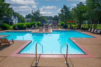 A large outdoor swimming pool surrounded by lounge chairs and trees. at The Addison at Collierville, Collierville, TN